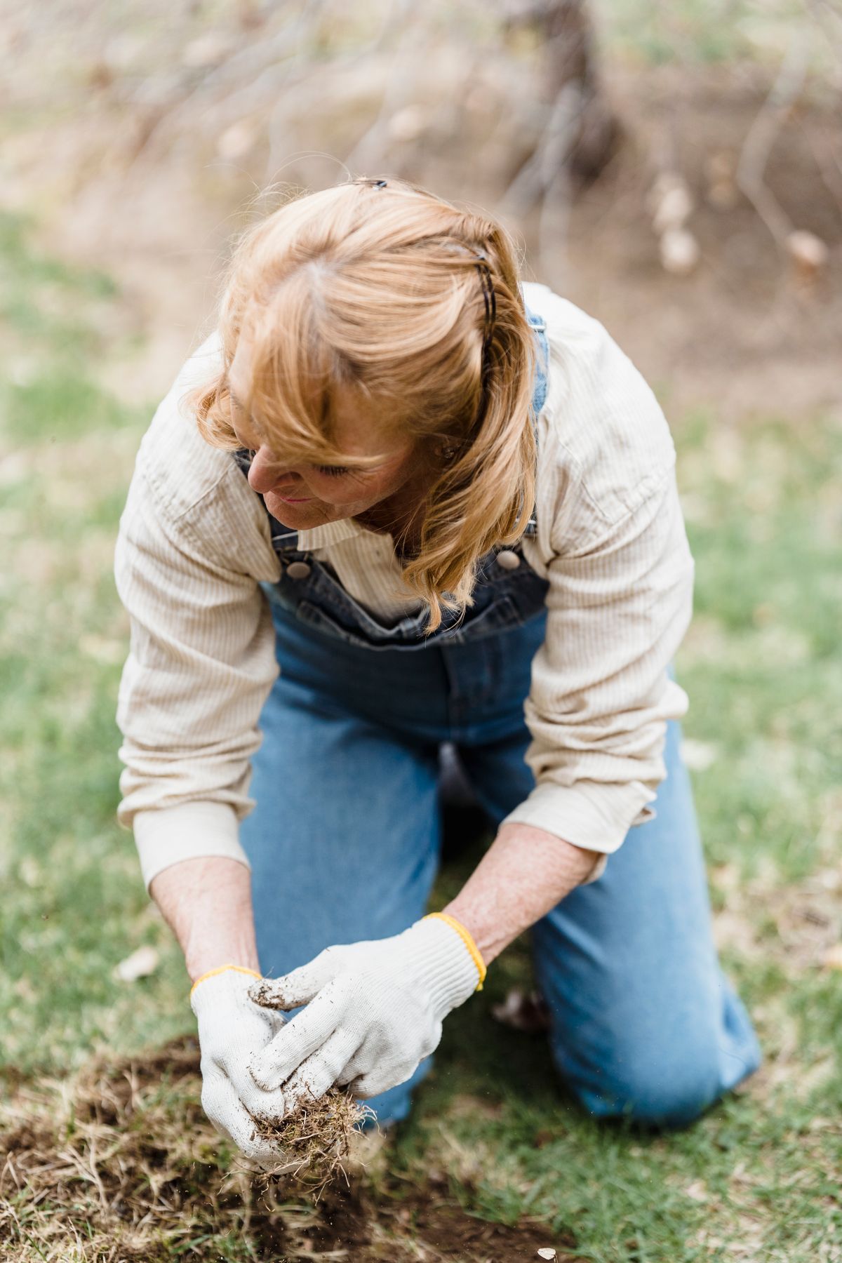 A Corbelway crew member kneeling in a yard, working the soil by hand